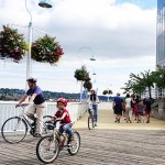 Father and son cycling on the boardwalk on New Westminster Pier. The pier is a great place for kids to practice their cycling skills.